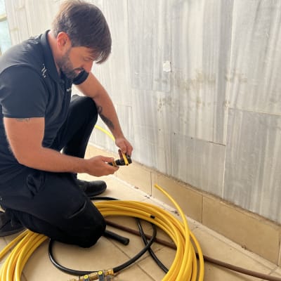 אדם עובד עם צינור גז צהוב וכלי עבודה