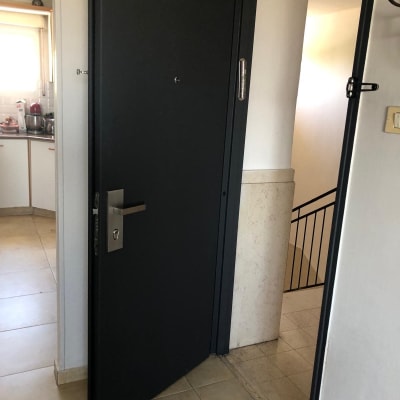 דלת מתכת כהה עם ידית כסופה פתוחה