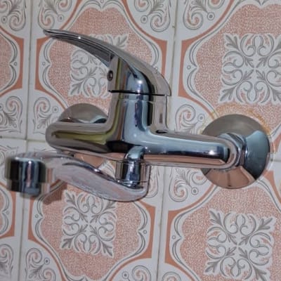 ברז כרום מותקן על קיר עם אריחים מעוצבים