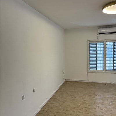 קיר צבוע בחדר עם רצפת עץ ותאורה עליונה