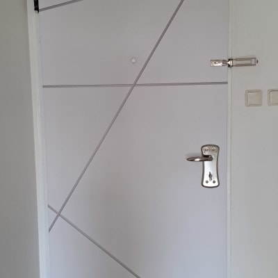 דלת לבנה עם עיטורים גיאומטריים ומנעול כסוף