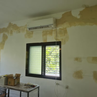 קיר עם תיקוני טיח וציוד צביעה על שולחן