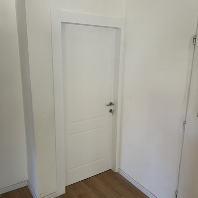 דלת לבנה עם ידית מתכת על רצפת עץ