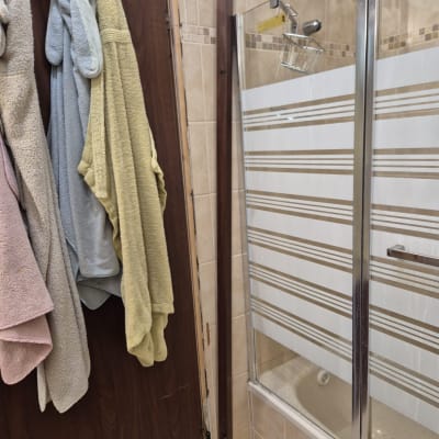 דלת עץ עם מגבות תלויים ומקלחון זכוכית