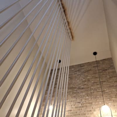 קיר לבנים עם מנורות תלויות וכתם צבע בתקרה