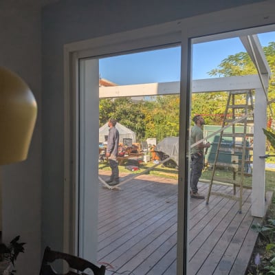 שני אנשים עובדים על פרגולה מעץ בגינה