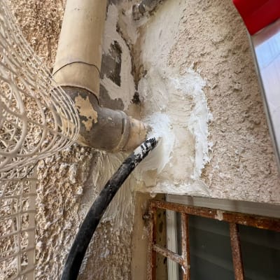 צינור אטום בחומר לבן על קיר חיצוני