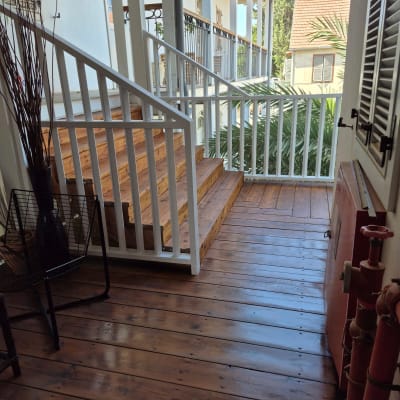 מרפסת עץ עם מעקה לבן ומדרגות עץ