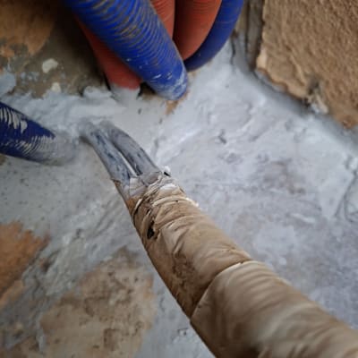 צינורות כחולים ואדומים עם חומר איטום על קיר