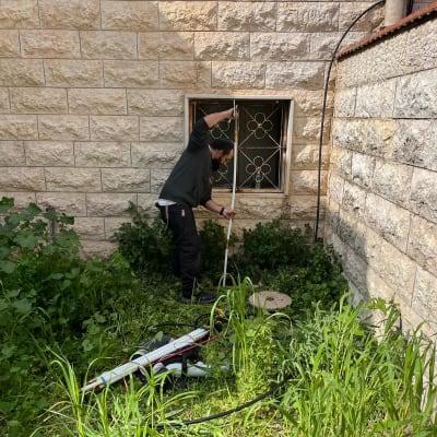 אדם עובד עם כלי אינסטלציה ליד מכסה ביוב