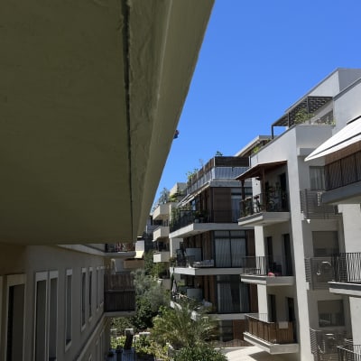 מרפסת עם כיסאות פלסטיק, בניינים ברקע, שמיים כחולים