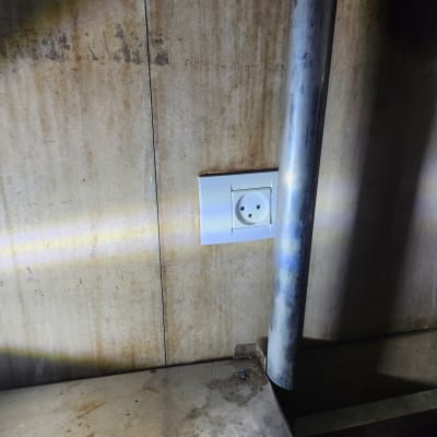 שקע חשמלי בקיר עם צינור מתכת לידו