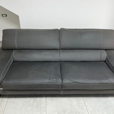 ספה אפורה עם תפרים לבנים על רצפת אריחים אפורה