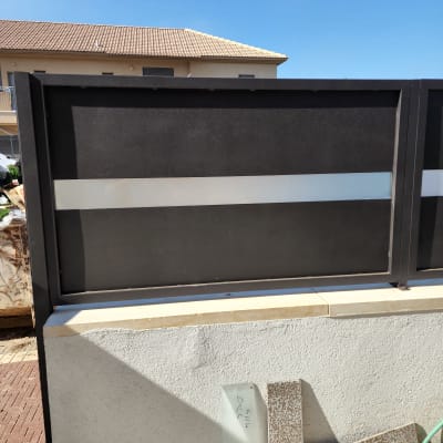 זכוכית מונחת על קיר לבן ליד גדר מתכת