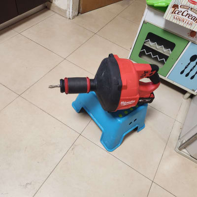 מכונת ניקוי צינורות אדומה על שרפרף כחול