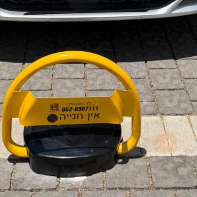 מחסום חניה צהוב על מדרכה ליד רכב