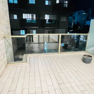 מרפסת נקייה עם רצפת אריחים ומעקה זכוכית