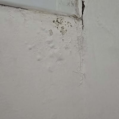 קיר עם סדקים ונזקי רטיבות ליד חלון