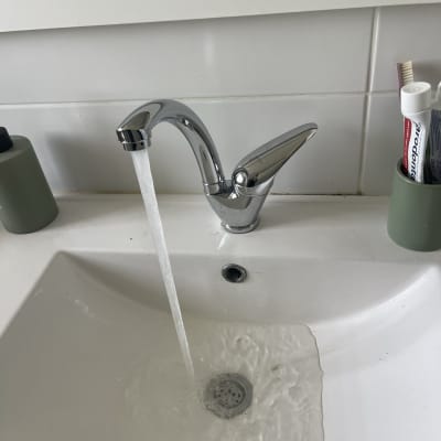 ברז מים זורם בכיור לבן עם ניקוז