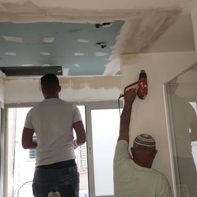 שני אנשים עובדים על תקרת גבס עם כלי עבודה