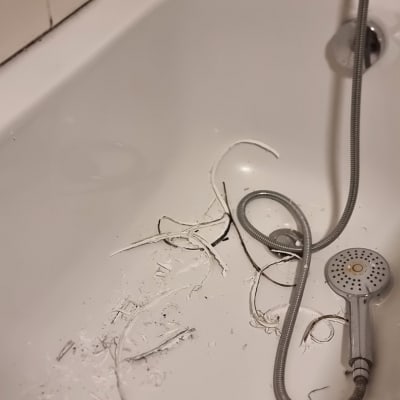 אמבטיה עם שאריות חומר איטום ומקלחת יד