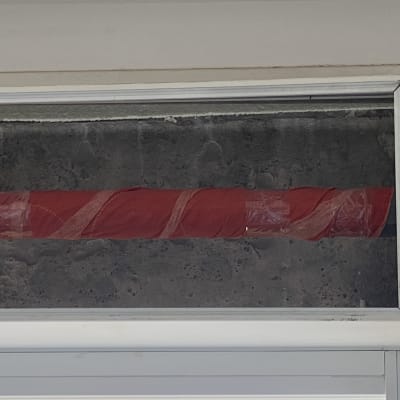 צינור עטוף בניילון אדום בתוך מסגרת חלון