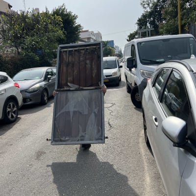 אדם נושא דוד שמש ברחוב בין מכוניות חונות