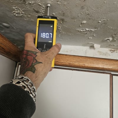 מד לחות נוגע בתקרה עם סימני רטיבות