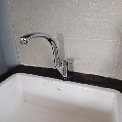 ברז כרום מותקן מעל כיור לבן עם ניקוז