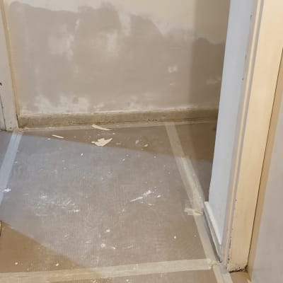 קיר עם תיקוני צבע ורצפה מכוסה בנייר