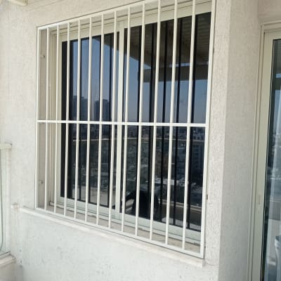 סורגי מתכת לבנים על חלון זכוכית