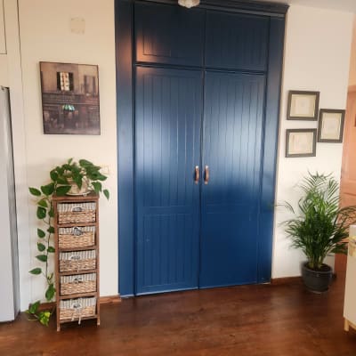 ארון עץ כחול עם ידיות, צמחייה ליד