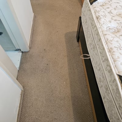 שטיח חום עם כתמים ליד מיטה