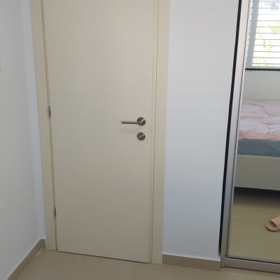 דלת לבנה עם ידית מתכת בחדר