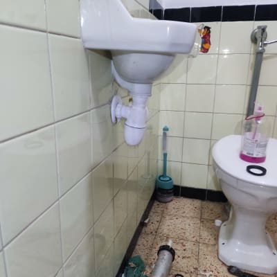 כיור עם צינור פתוח וכלי עבודה על הרצפה