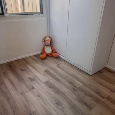 רצפת פרקט עם בובה ליד ארון וחלון