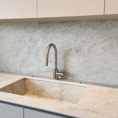 כיור מטבח עם ברז נירוסטה על רקע שיש אפור