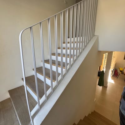 מעקה מתכת לבן על גרם מדרגות עץ