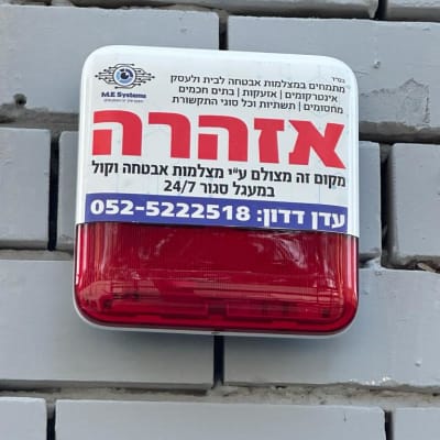 שלט אזהרה על קיר עם פרטי מצלמות אבטחה