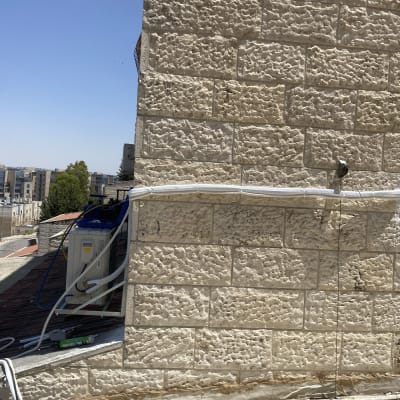 יחידת מיזוג אוויר מותקנת על קיר חיצוני עם צינורות מחוברים
