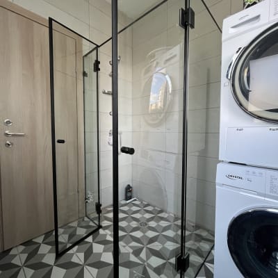 מקלחון זכוכית בחדר אמבטיה עם מכונת כביסה