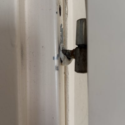 ציר דלת מתכת מותקן במסגרת דלת לבנה