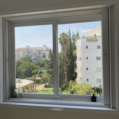 חלון עם נוף של בניינים ועצים בחוץ