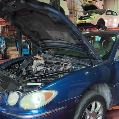 רכב במוסך עם מכסה מנוע פתוח, רכבים נוספים ברקע