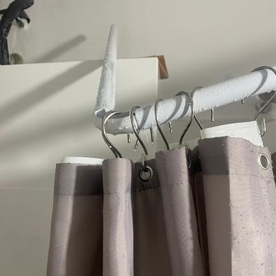 וילון מקלחת תלוי על מוט עם טבעות מתכת