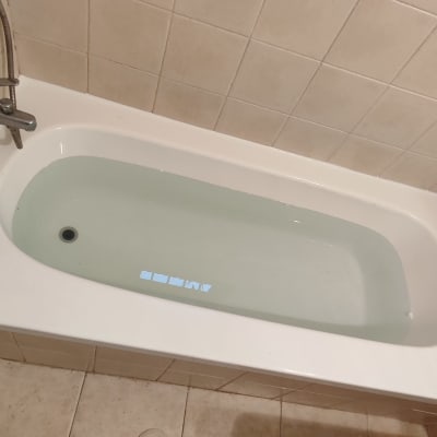 אמבטיה מלאה מים עם ברז מתכת על קיר מרוצף