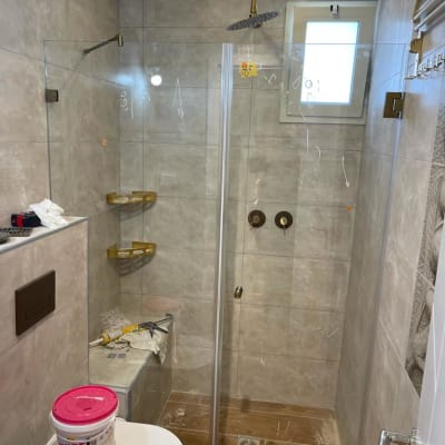 מקלחון זכוכית עם ראש מקלחת זהוב ומדפים