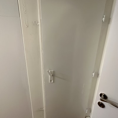 דלת לבנה עם ידית כסופה על רקע קיר לבן