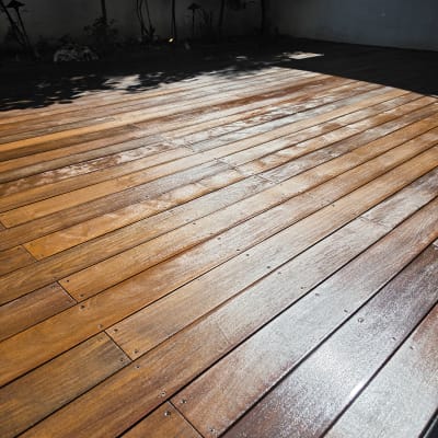 דק עץ בגינה עם צללים ועצים ברקע