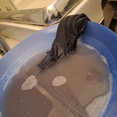 קערה כחולה עם מים וסבון, בגד שחור בתוכה